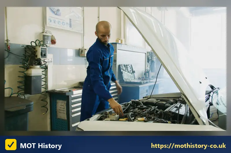 Mechanic examining an engine under a raised bonnet in a workshop - car mot history check free