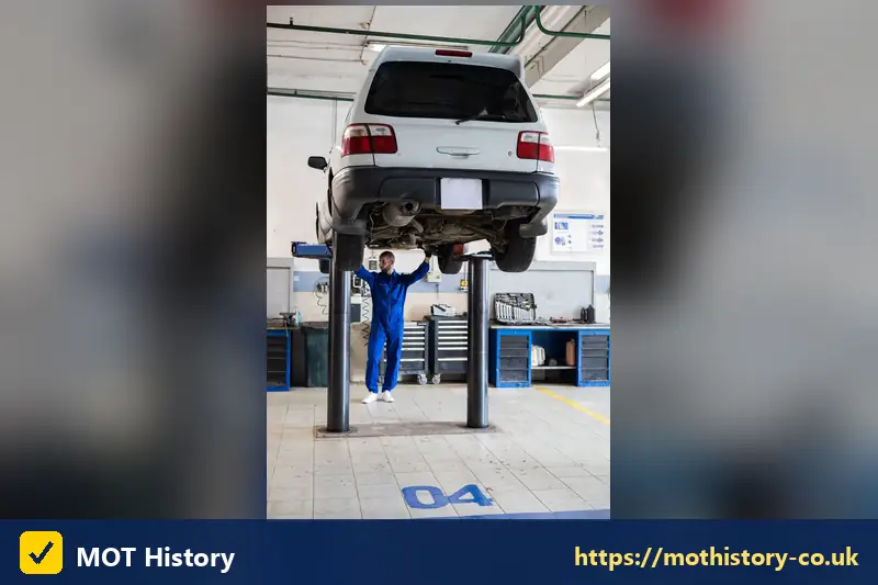 Car raised on a lift with a mechanic standing beneath it - category d meaning