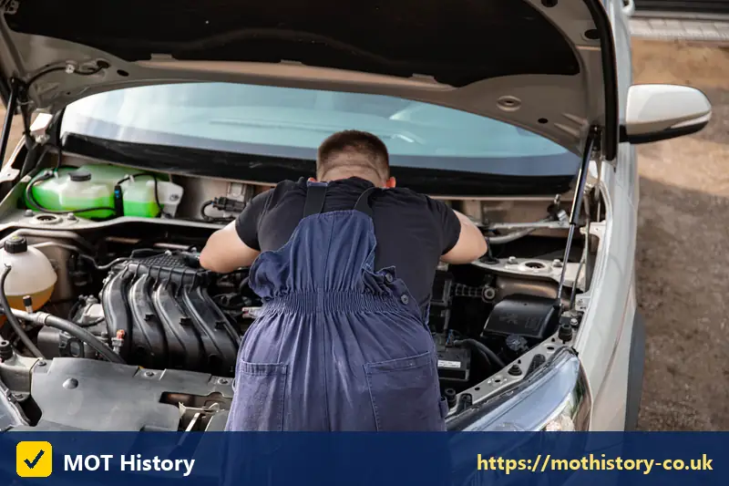 Mechanic bending over a car engine bay - caz charge