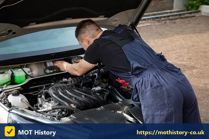 Mechanic checking a car engine with the bonnet raised - caz charge