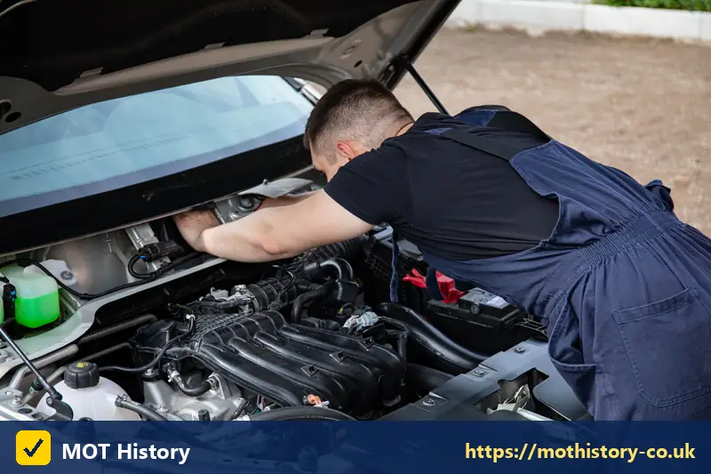 Mechanic inspecting a car engine with the bonnet up - change mot appointment
