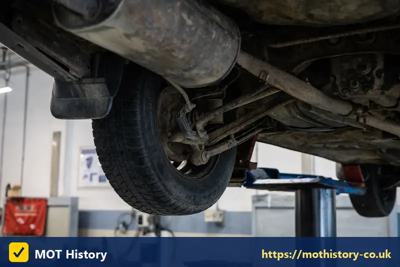 Exhaust and suspension underneath a car on a lift - check finance letter