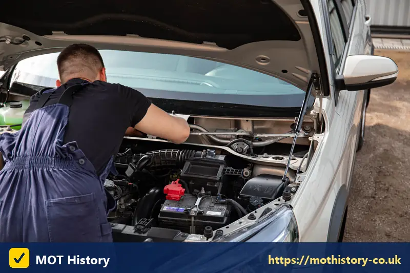 Mechanic checking the battery and engine of a silver car - check hp