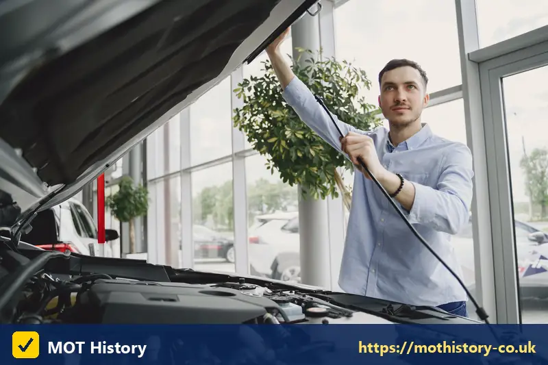 Man checking under the bonnet of a car in a showroom - comprehensive vehicle insurance