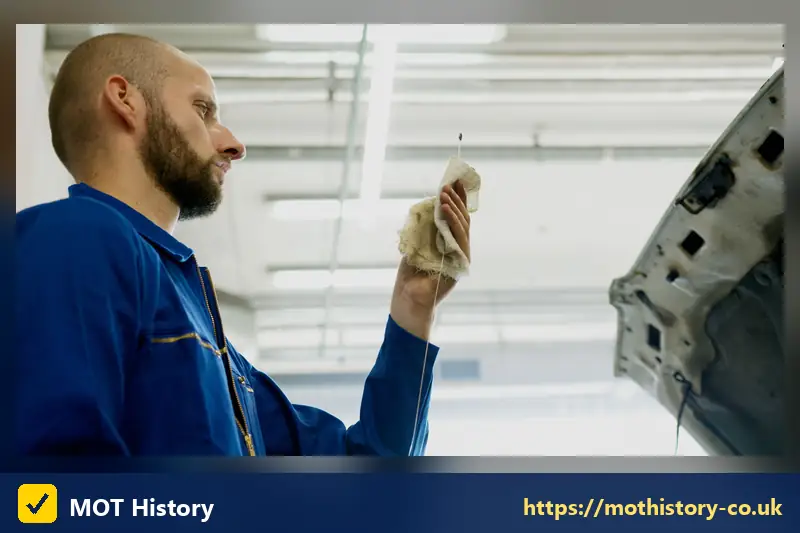 Mechanic wiping a dipstick beside an open bonnet - mot and service deals