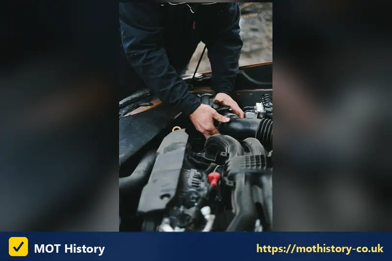 Hands working on a car engine - mot before due date