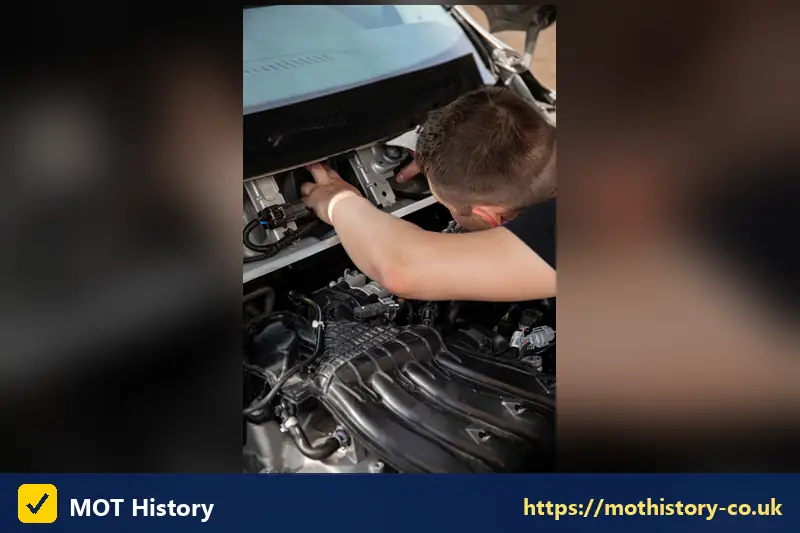 Mechanic looking closely at parts in the engine bay - mot history northern ireland