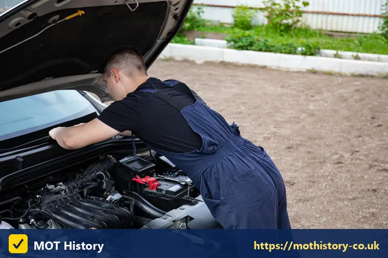 Mechanic in overalls checking a car engine outdoors - mot price