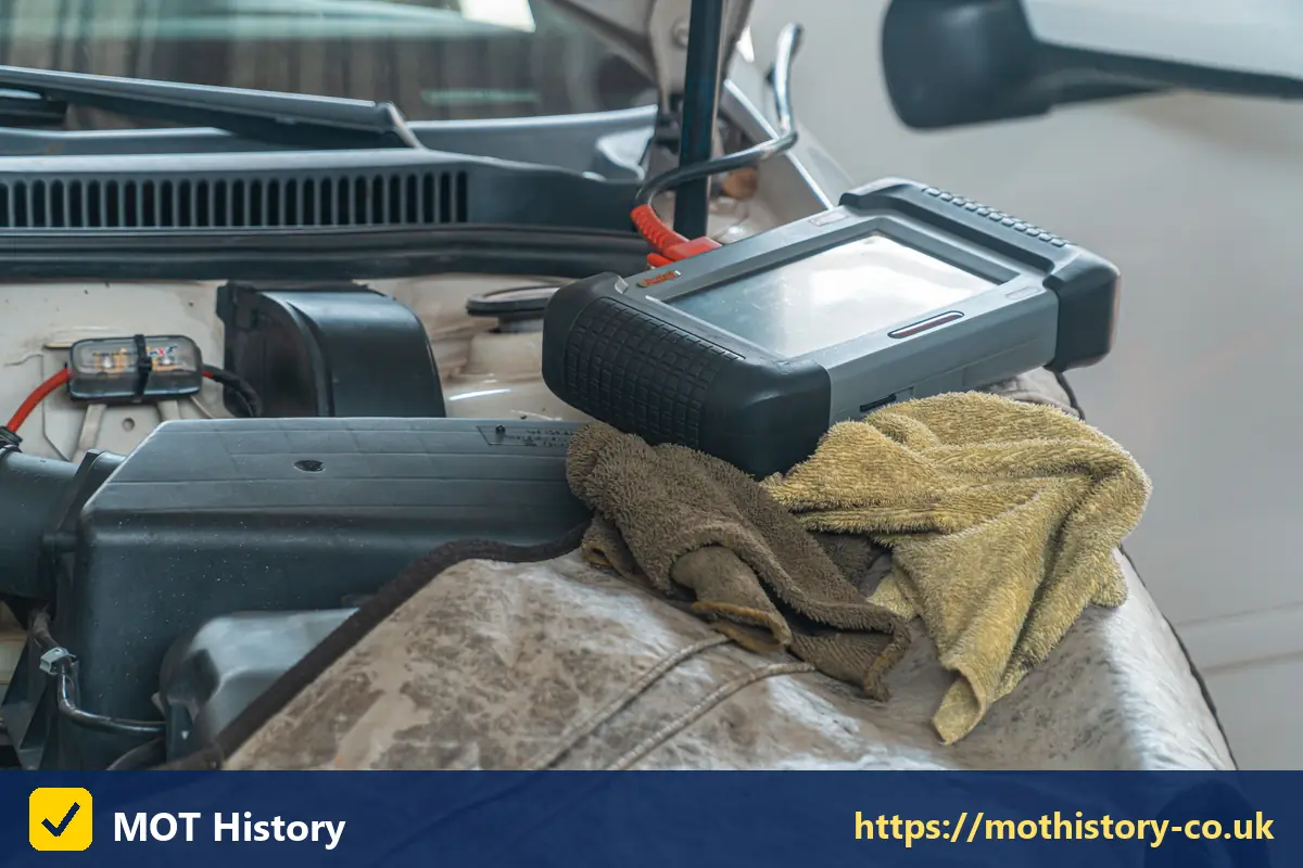 Diagnostic tablet resting on a car engine - check if a car has been written off