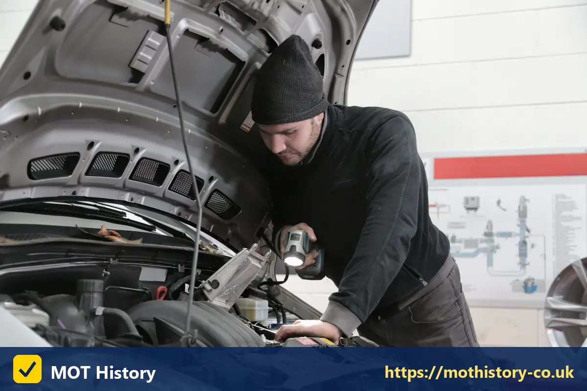 Mechanic inspecting an engine with a torch - co2 emissions checker