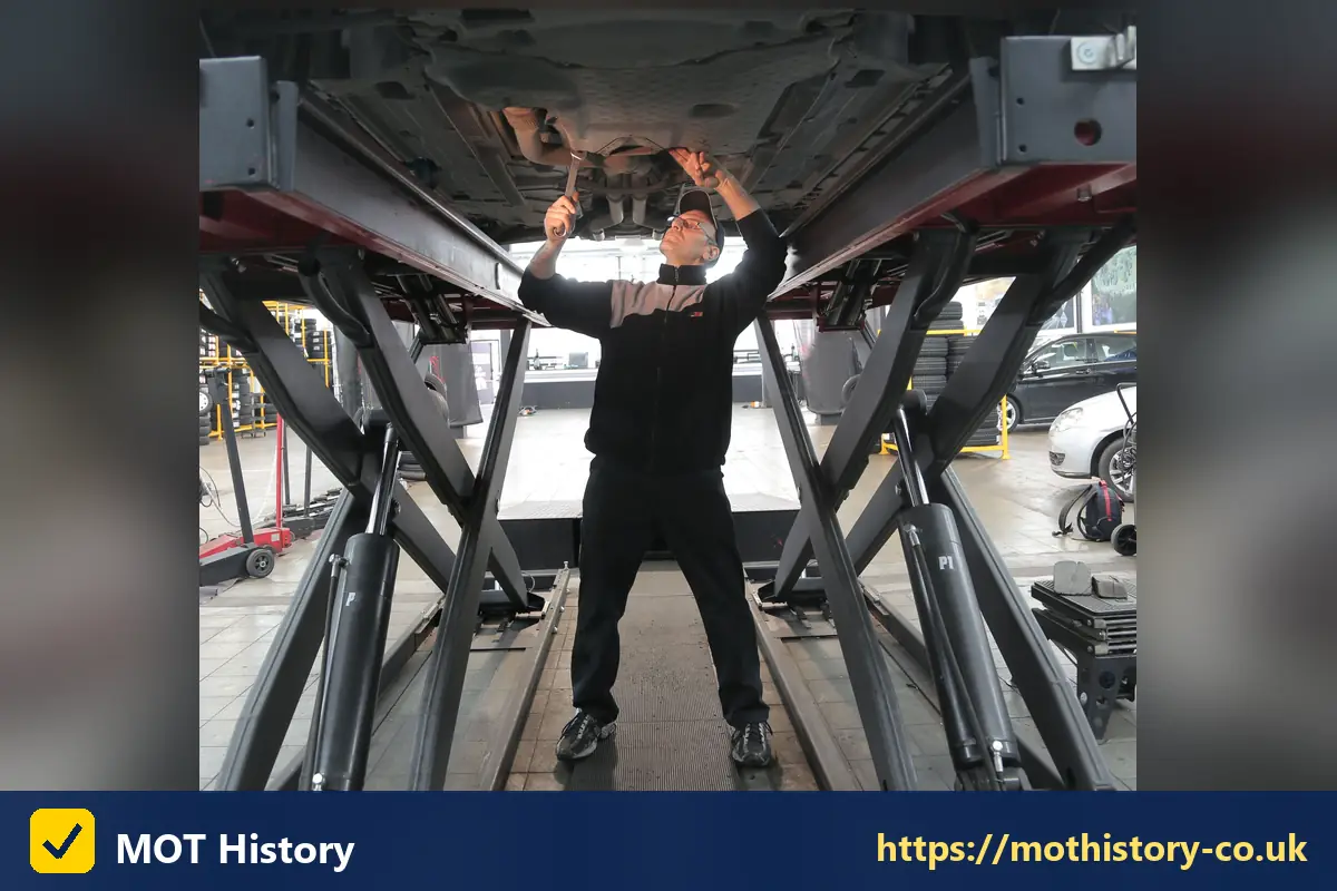Mechanic inspecting the underside of a car on a scissor lift - when is my mot due